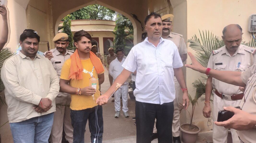 पावटा में ड्रिप लगी हालत में प्रागपुरा थाने के गेट पर लेट गए पूर्व सरपंच, मारपीट का लगाया आरोप