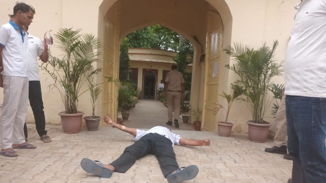 पावटा में ड्रिप लगी हालत में प्रागपुरा थाने के गेट पर लेट गए पूर्व सरपंच, मारपीट का लगाया आरोप